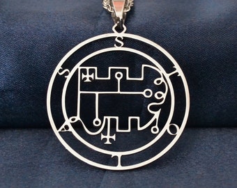 May include: A silver necklace with a circular pendant featuring a detailed, intricate design. The pendant is a sigil, a symbol used in magic and ritual.