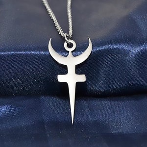 Può includere: Una collana con un ciondolo d'argento che presenta un simbolo stilizzato con una luna crescente, una croce e un pugnale. Il ciondolo è appeso a una catena d'argento su uno sfondo blu scuro.