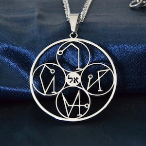 Può includere: Una collana d'argento con un ciondolo circolare che presenta quattro simboli geometrici. Il ciondolo è in metallo e ha una finitura lucida.
