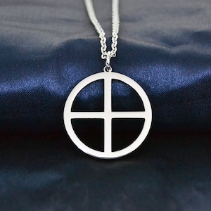 Könnte beinhalten: Eine silberne Halskette mit einem runden Anhänger, der ein Kreuzdesign aufweist. Der Anhänger ist hohl und hat eine glatte, polierte Oberfläche.