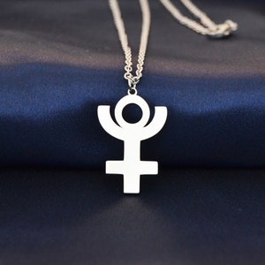 Könnte beinhalten: Eine silberne Kettenkette mit einem weißen Metallanhänger, der das astrologische Symbol für Uranus zeigt.