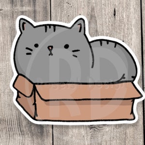 May include: A gray cartoon cat with a pink nose sits inside a brown cardboard box. The cat is looking at the viewer with a neutral expression.