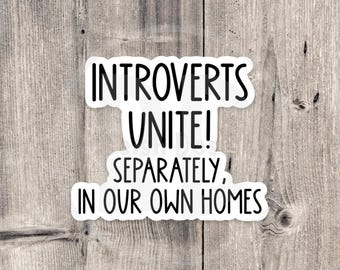 May include: A white sticker with black text on a wooden background. The sticker reads "Introverts Unite! Separately, In Our Own Homes."