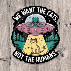 May include: A sticker with a cartoon alien in a flying saucer, a cat sitting in a beam of light, and the text "We want the cats, not the humans."