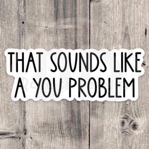May include: A white sticker with the phrase "THAT SOUNDS LIKE A YOU PROBLEM" in black, sans-serif font. The sticker has a scalloped edge and is set against a weathered, gray wooden background.
