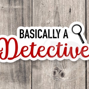 May include: A white sticker with the text "Basically A Detective" in black and red, with a magnifying glass icon. The sticker is on a wooden background.