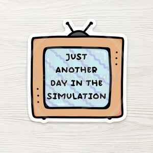 May include: A sticker featuring a retro television with the text "JUST ANOTHER DAY IN THE SIMULATION." The TV has a light orange frame, a blue screen with wavy lines, and black antenna.