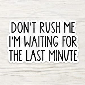 May include: A white sticker with black text that reads "DON'T RUSH ME I'M WAITING FOR THE LAST MINUTE." The sticker has a rounded rectangle shape and is set against a light wood grain background.