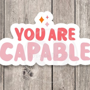 May include: A white sticker with a pink and red gradient design. The sticker says "You are capable" with a star design above the text.