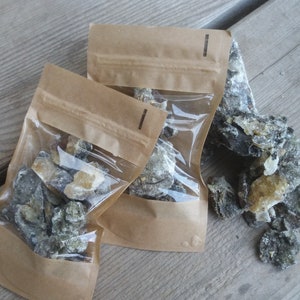 May include: Three brown paper bags with clear plastic windows, each containing a pile of dark gray and light brown resin pieces.