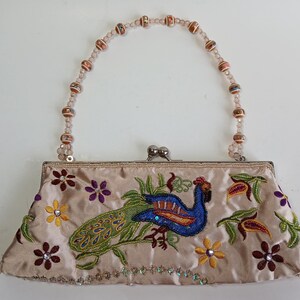 Bolso de mano MCM de satén con bordado de pavo real y cuentas decorativas, con asa superior y cierre de beso