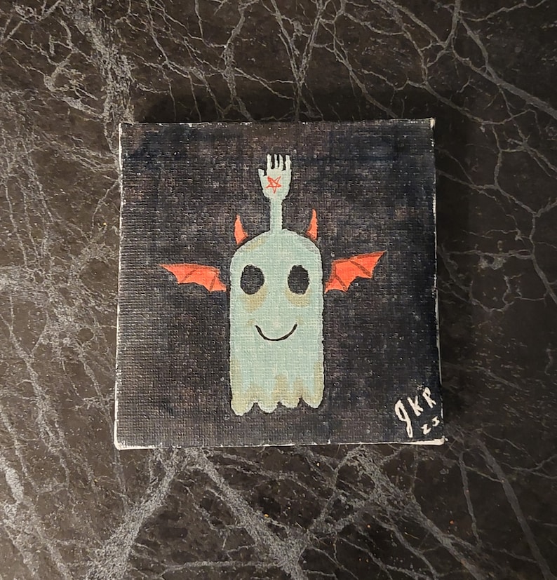 Op de afbeelding: Een handgeschilderd canvas met een grillige geest met rode duivelshoorns en vleugels. De geest is geschilderd in tinten blauw en groen, met een vriendelijke glimlach. De achtergrond is een donker, getextureerd zwart. Het canvas is rechtsonder getekend met "gkr 23".