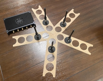 May include: A black device with multiple antennas and a heat sink, surrounded by six brown cardboard circles with cutouts for the antennas. The device is on a wooden surface.