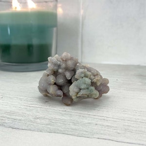 May include: A cluster of purple and green agate, a type of chalcedony, with a rough, textured surface. The agate is a natural stone with a unique and beautiful pattern.