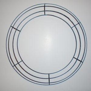 May include: A round metal wreath frame with three concentric circles. The frame is made of thin wire and is silver in color.