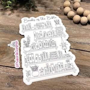 May include: A white sticker featuring a bookshelf design with the words "Books of the Bible" at the top. The sticker lists the books of the Bible on the shelves, with potted plants on each shelf. The sticker has a white border.
