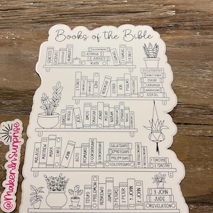 May include: A white sticker featuring a bookshelf design with the words "Books of the Bible" at the top. The shelves are filled with book titles from the Bible, and there are potted plants on the shelves. The sticker has a white border.