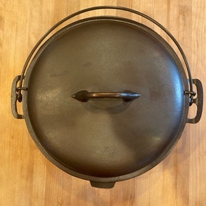 Pode incluir: Uma panela de ferro fundido com tampa e duas alças. A tampa tem uma alça de madeira.