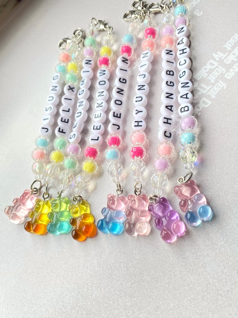 May include: Eight colorful beaded keychains with gummy bear charms. Each keychain features a different name: Jisung, Felix, Seungmin, Leeknow, Jeongin, Hyunjin, Changbin, and Bangchan.