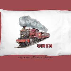 May include: A white pillowcase with a red and black steam train with smoke coming from the chimney. The train is on a track and the words "OWEN" are printed below the train. The words "From the Meadow Designs" are printed at the bottom of the pillowcase.