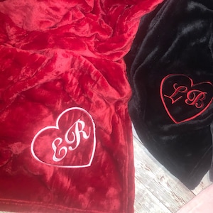 May include: Two plush blankets with embroidered hearts. One blanket is red with a white heart that says "E&R" and the other blanket is black with a red heart that says "L&B".
