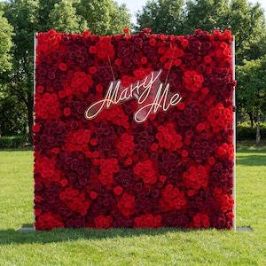 Peut inclure: Un grand fond carré recouvert de roses rouges et bordeaux. Une enseigne au néon avec l'inscription "Marry Me" est suspendue au centre. La toile de fond est installée sur une pelouse herbeuse avec des arbres en arrière-plan.