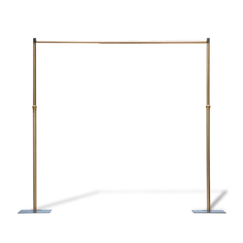 This sleek, minimalist structure is a gold-toned metal frame (likely an event backdrop stand) with two tall vertical poles, a horizontal top bar, and square base plates for stability. The polished brass-like finish gives it a modern, elegant look, while adjustable joints (visible on the poles) suggest versatility for different setups. Set against a plain white background, it appears lightweight yet sturdy—ideal for supporting backdrops, drapes, or decor at weddings, parties, or other events.