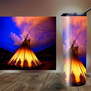 May include: A stainless steel tumbler with a colorful image of a teepee with silhouettes of people inside. The teepee is lit from within, casting a warm glow. The background is a vibrant sunset sky with clouds.