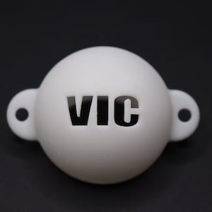 May include: White plastic ball with a black "VIC" cutout. The ball has two small loops on either side.
