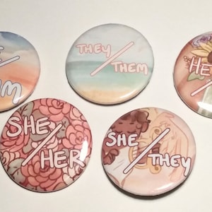 Op de afbeelding: Zes ronde knoppen met verschillende achtergronden en tekst. De tekst op de knoppen luidt "He/Him", "She/Her", "She/They", "He/They", "They/Them".