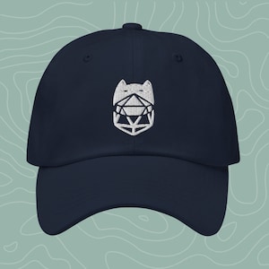 May include: A navy blue baseball cap with a white embroidered logo of a stylised cat head with a geometric shape inside.