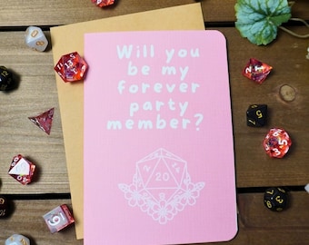 May include: A pink card with white text that reads "Will you be my forever party member?" and a white illustration of a twenty-sided die with flowers around it.
