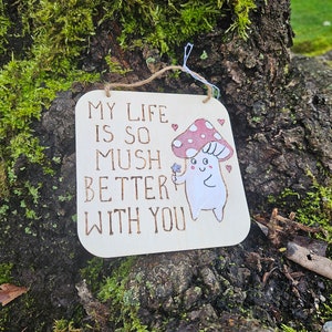 Puede incluir: Un letrero de madera con un personaje de hongo y el texto "My life is so mush better with you".