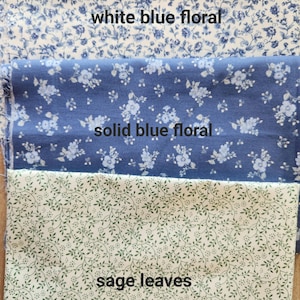 May include: Three fabric swatches with floral and leaf patterns. The top swatch is white with blue floral designs, the middle swatch is solid blue with white floral designs, and the bottom swatch is white with sage green leaves. Text on the image reads "white blue floral", "solid blue floral", and "sage leaves".