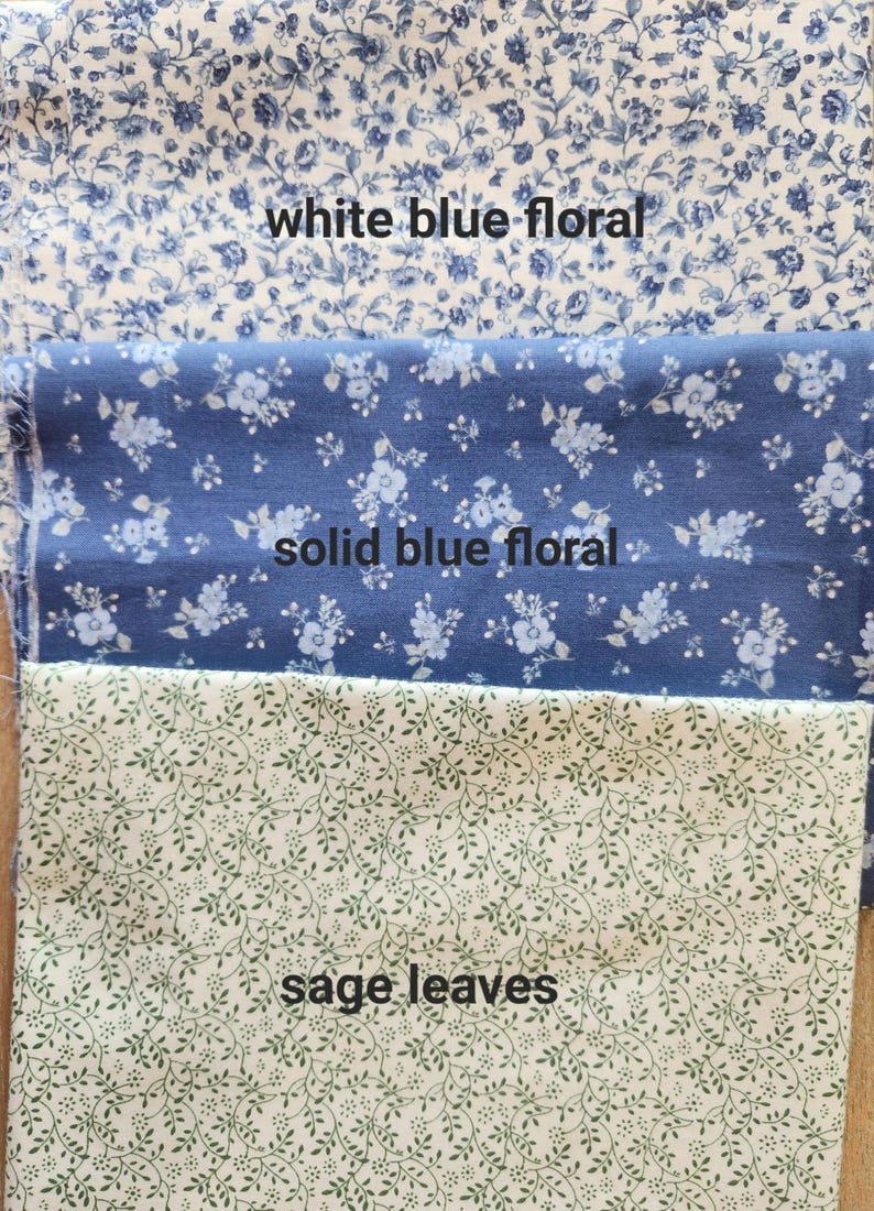 May include: Three fabric swatches with floral and leaf patterns. The top swatch is white with blue floral designs, the middle swatch is solid blue with white floral designs, and the bottom swatch is white with sage green leaves. Text on the image reads "white blue floral", "solid blue floral", and "sage leaves".