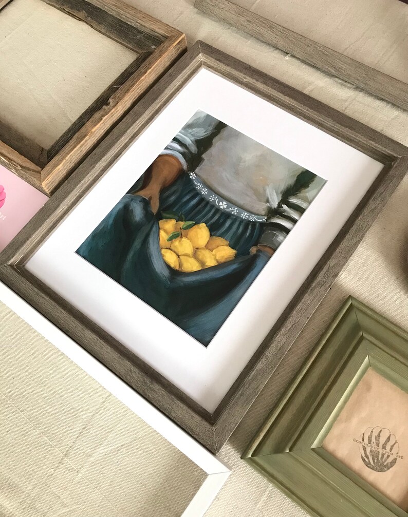 May include: A framed painting of a person holding a basket of lemons. The person is wearing a blue and white striped shirt and a blue skirt. The lemons are yellow and are arranged in a basket.