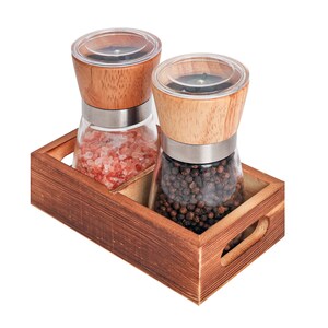 Peut inclure: Un plateau en bois contient deux moulins &agrave; sel et &agrave; poivre en verre. L'un contient du sel rose de l'Himalaya, l'autre des grains de poivre noir. Les deux ont des couvercles en bois et des bandes en acier inoxydable. Le plateau est en bois teint&eacute;.