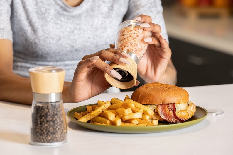 Peut inclure: Un moulin &agrave; sel en verre avec un dessus en bois est utilis&eacute; pour assaisonner un hamburger et des frites sur une assiette verte. Le burger contient du bacon et du fromage. Un moulin &agrave; poivre est &agrave; proximit&eacute;.
