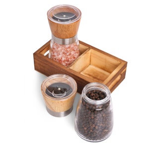 Peut inclure: Un ensemble de moulins &agrave; sel et &agrave; poivre en bois avec un plateau en bois. L'ensemble comprend un moulin &agrave; sel rempli de sel rose de l'Himalaya, un moulin &agrave; poivre et un bocal en verre rempli de grains de poivre. Les moulins ont des dessus en bois et des fen&ecirc;tres de visualisation en plastique transparent.