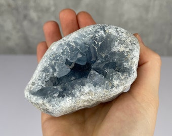 May include: A blue celestite geode with a natural, rough exterior and a hollow interior lined with sparkling blue crystals.