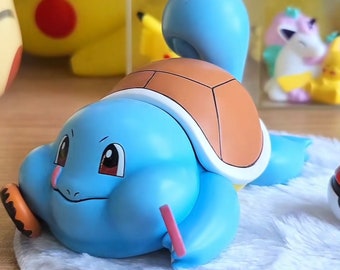 May include: A blue and brown Squirtle figurine with a light blue shell and a brown shell. The figurine is lying on its side with its head resting on its shell. The figurine is made of plastic and has a cartoonish appearance.