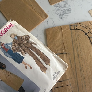 May include: A collection of vintage sewing patterns, including a Pierre Balmain design, with illustrations of clothing and pattern pieces. The patterns are in various brown paper envelopes and sheets, with some showing diagrams and instructions.