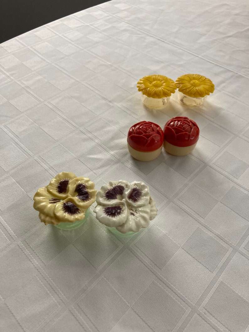 May include: Set of six vintage ceramic salt and pepper shakers with floral designs. Two yellow flower shakers, two red flower shakers, and two pansy shakers, one yellow and one white.