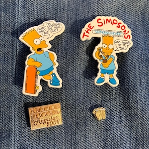 May include: A collection of The Simpsons themed pins and stickers. Two stickers feature Bart Simpson with speech bubbles. One pin is rectangular with the text "Warehouse House Regular 2009". A small pin of a baseball glove is also included.