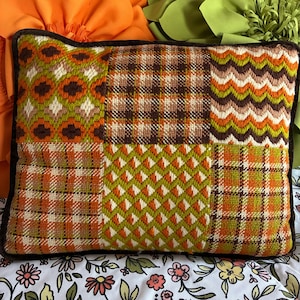 May include: Rectangular patchwork pillow with a brown border. The pillow features various geometric patterns in orange, brown, green, and cream. The patterns include floral, plaid, and zigzag designs, creating a vintage aesthetic.