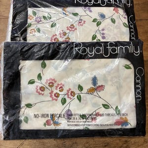 May include: Two twin fitted bottom sheets in plastic packaging. The sheets are white with a floral pattern in pink, blue, and green. The packaging reads "Royal Family" and "Cannon". The sheets are 39 x 76 inches.