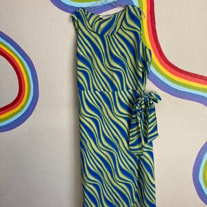 May include: A sleeveless green and blue dress with a wavy stripe pattern. The dress has a wrap style and a tie at the waist.