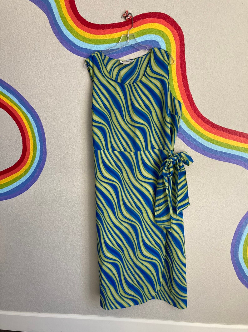 May include: A sleeveless green and blue dress with a wavy stripe pattern. The dress has a wrap style and a tie at the waist.