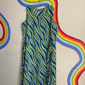 May include: A sleeveless maxi dress with a blue and green wavy pattern. The dress has a scoop neck and a tie at the waist.