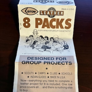 May include: A vintage package of 8 leather craft kits, designed for group projects. The package features a cartoon illustration of children working on a craft project together. The text on the package reads "Genuine Leather Kit 8 Packs "8 of a kind for group fun activity!" Designed for Group Projects Scouts Camps Clubs Schools Indian Guides Made in U.S.A."